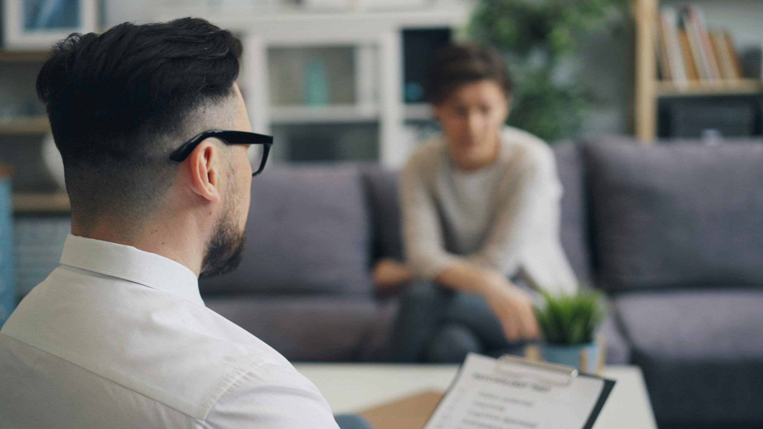 Nosotros A therapist and patient engaged in a discussion during a session inside an office setting.